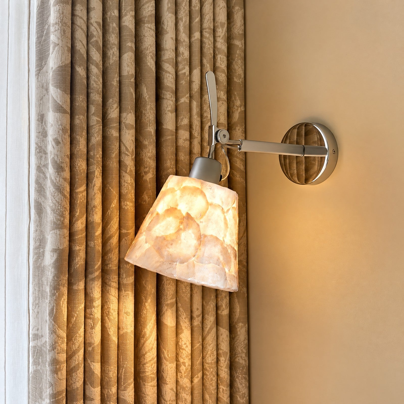 Shell-inspired wall sconce against warm curtains